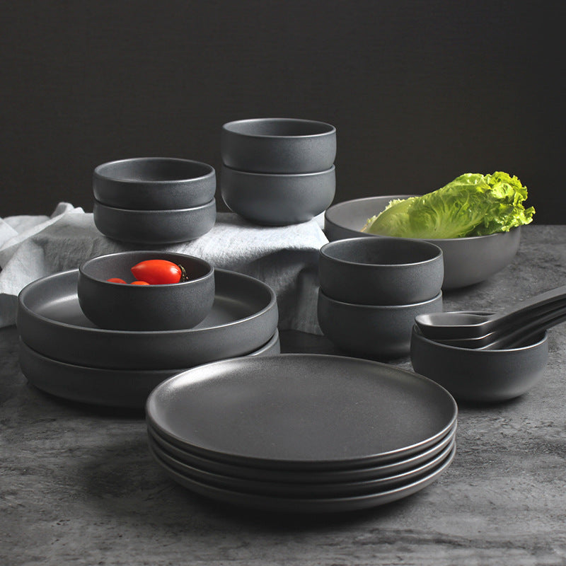 Matte grey Nordic ceramic rice bowl and deep steak plate with organic rims on a slate coaster.